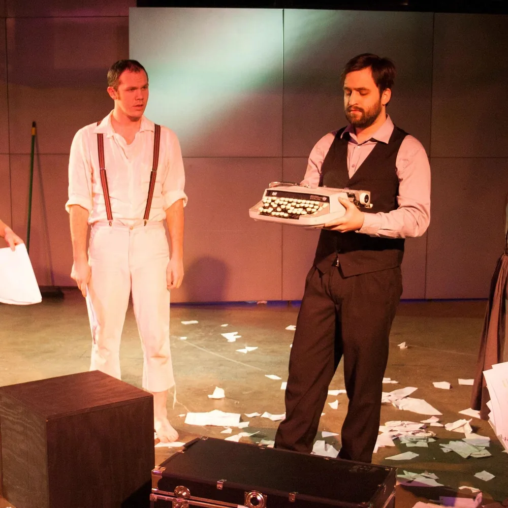 Dinner guests in costume lean over their plates and scripts at a long candlelit table during a mystery show